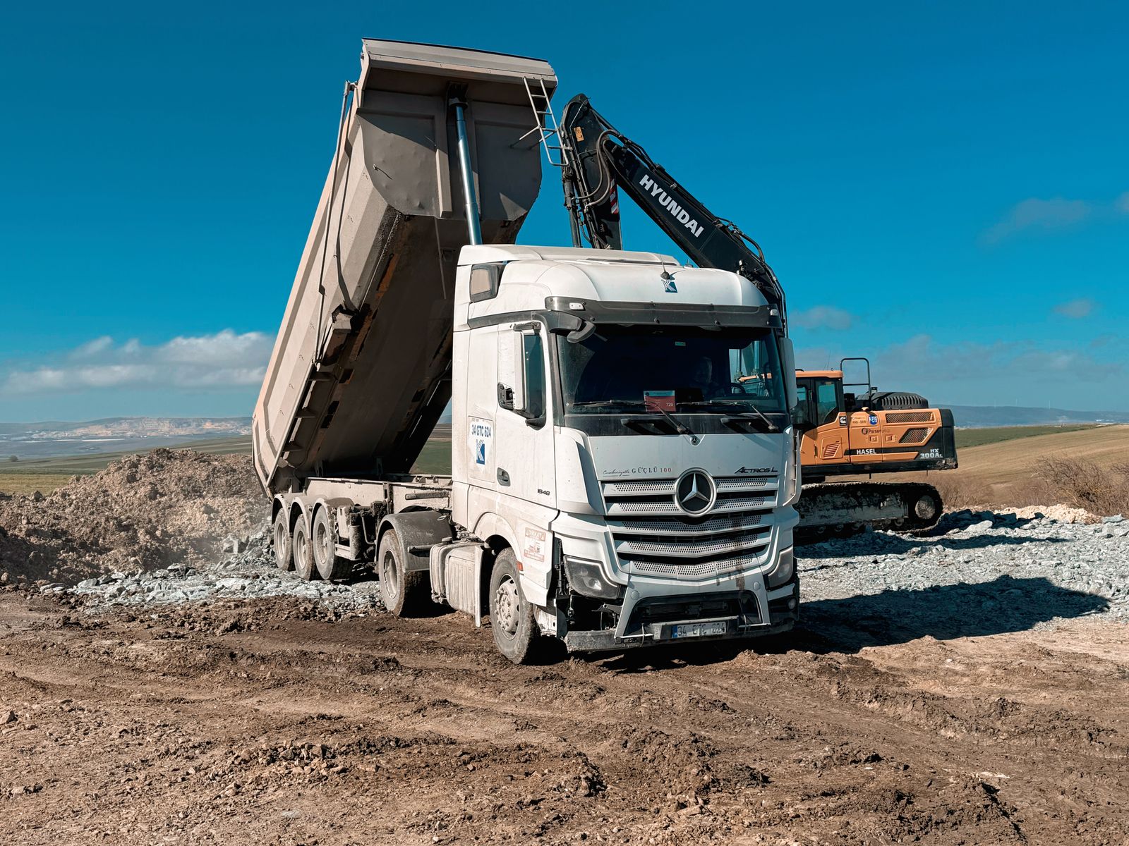 Mercedes-Benz tipper truck and excavator on site